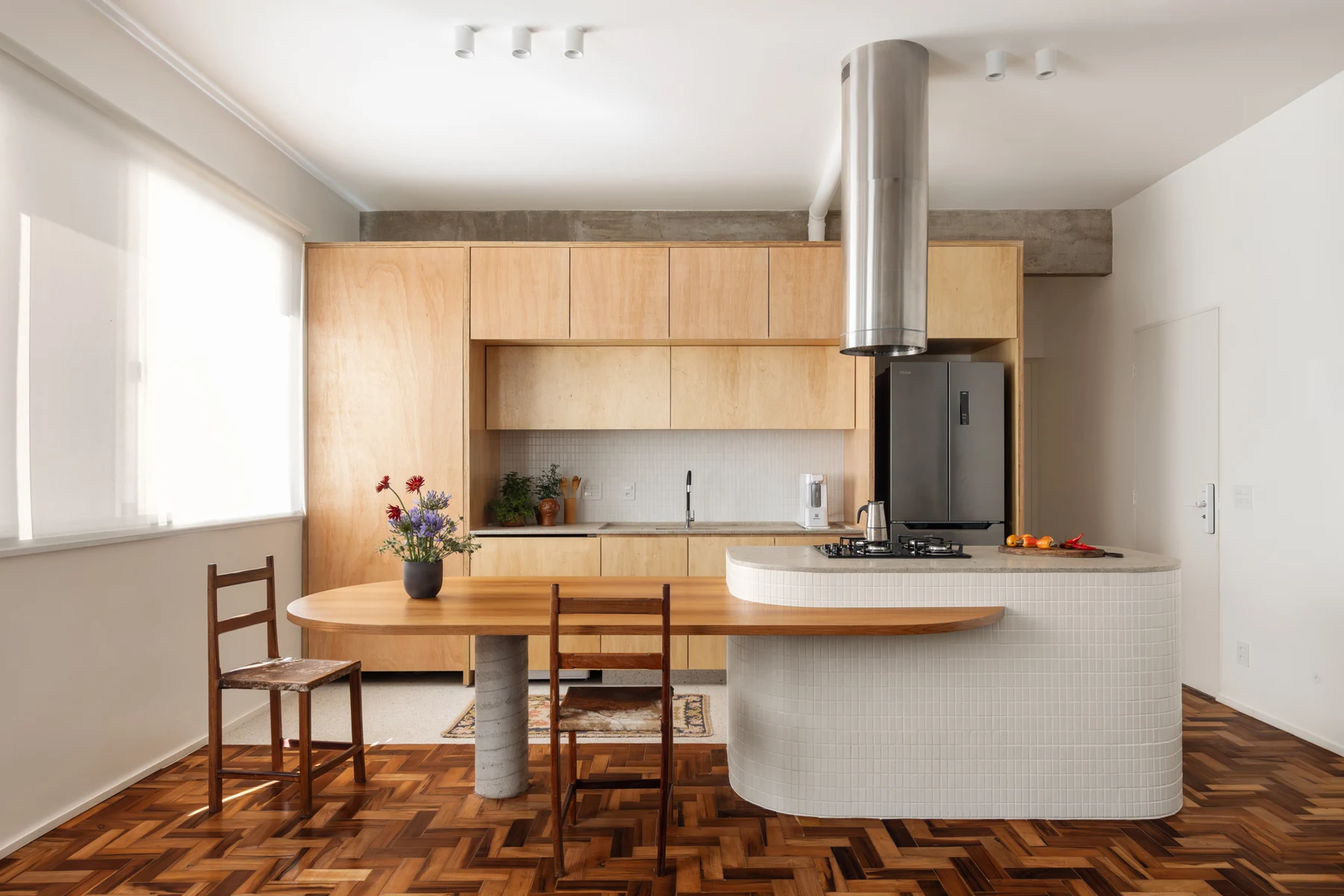 Timber kitchen with rounded cooking peninsula and adjoining dining table