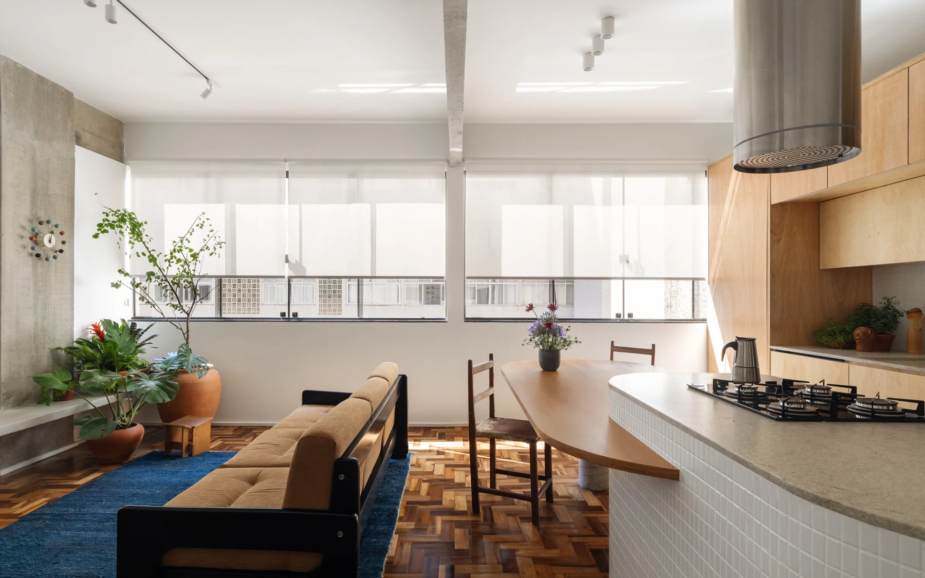 Open-plan living area with the sofa back facing the kitchen and dining table