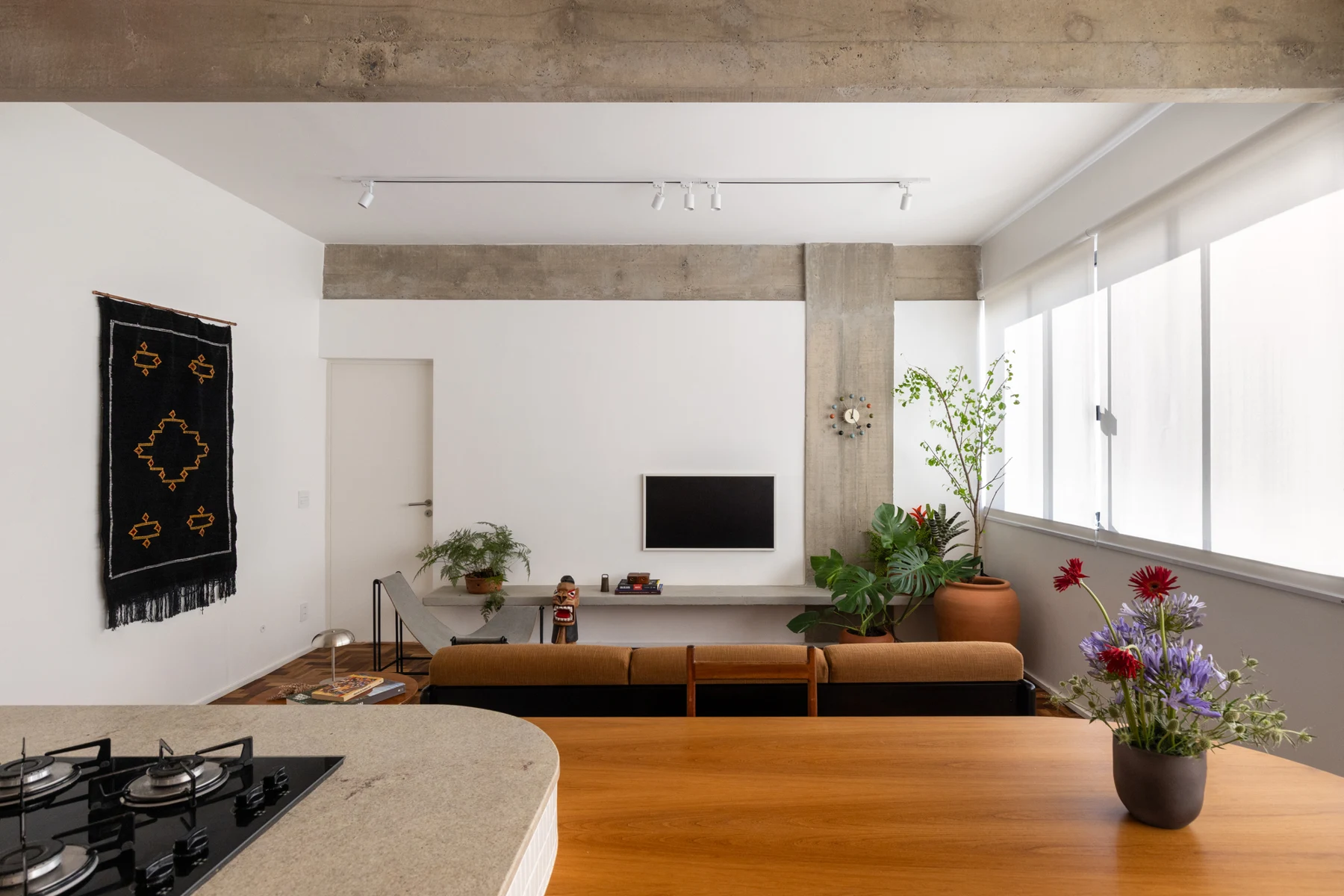 View from the kitchen across the dining surface towards the back of the sofa and television