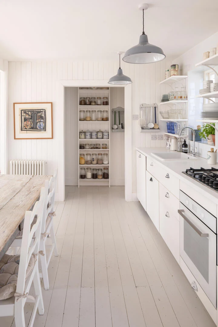 White kitchen cabinetry, worktop, panelling and painted floor