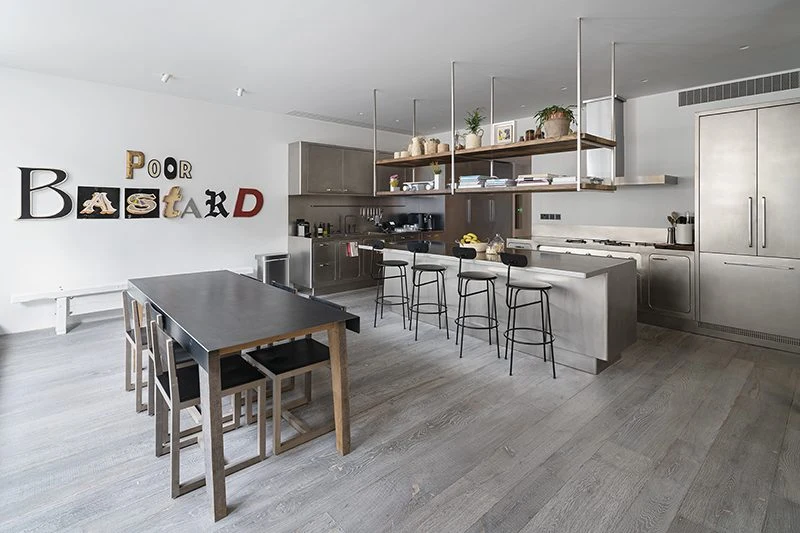 Open-plan stainless-steel kitchen with an island, suspended shelves and adjoining dining area