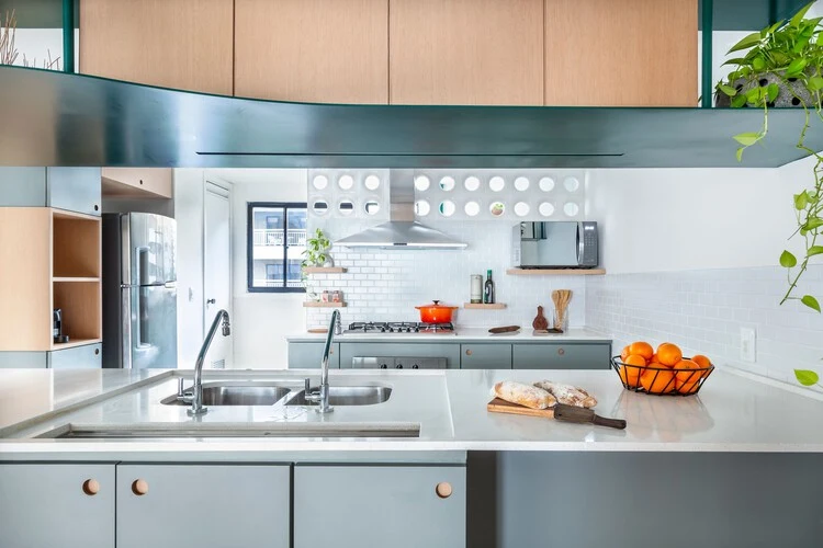 Kitchen worktop beneath timber upper cupboards and a green metal shelf with a slim integrated light