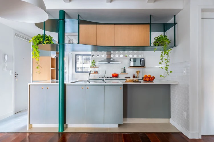 Kitchen with grey lower cabinetry and a separate suspended green metal frame containing timber cupboards
