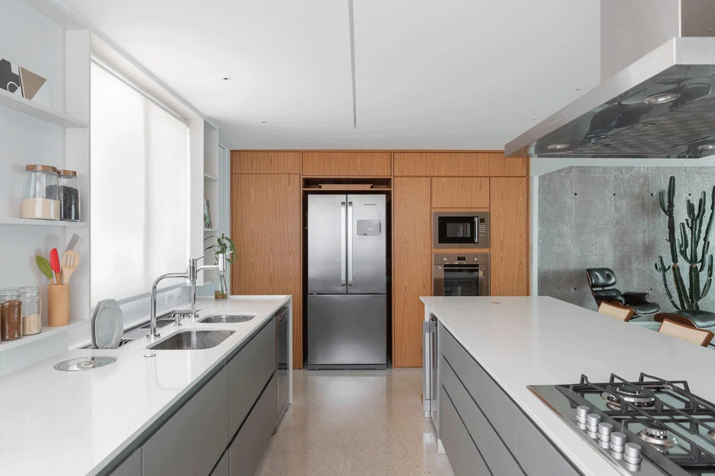 Kitchen with full-height timber cabinetry, white worktops and grey lower units beside an exposed concrete wall