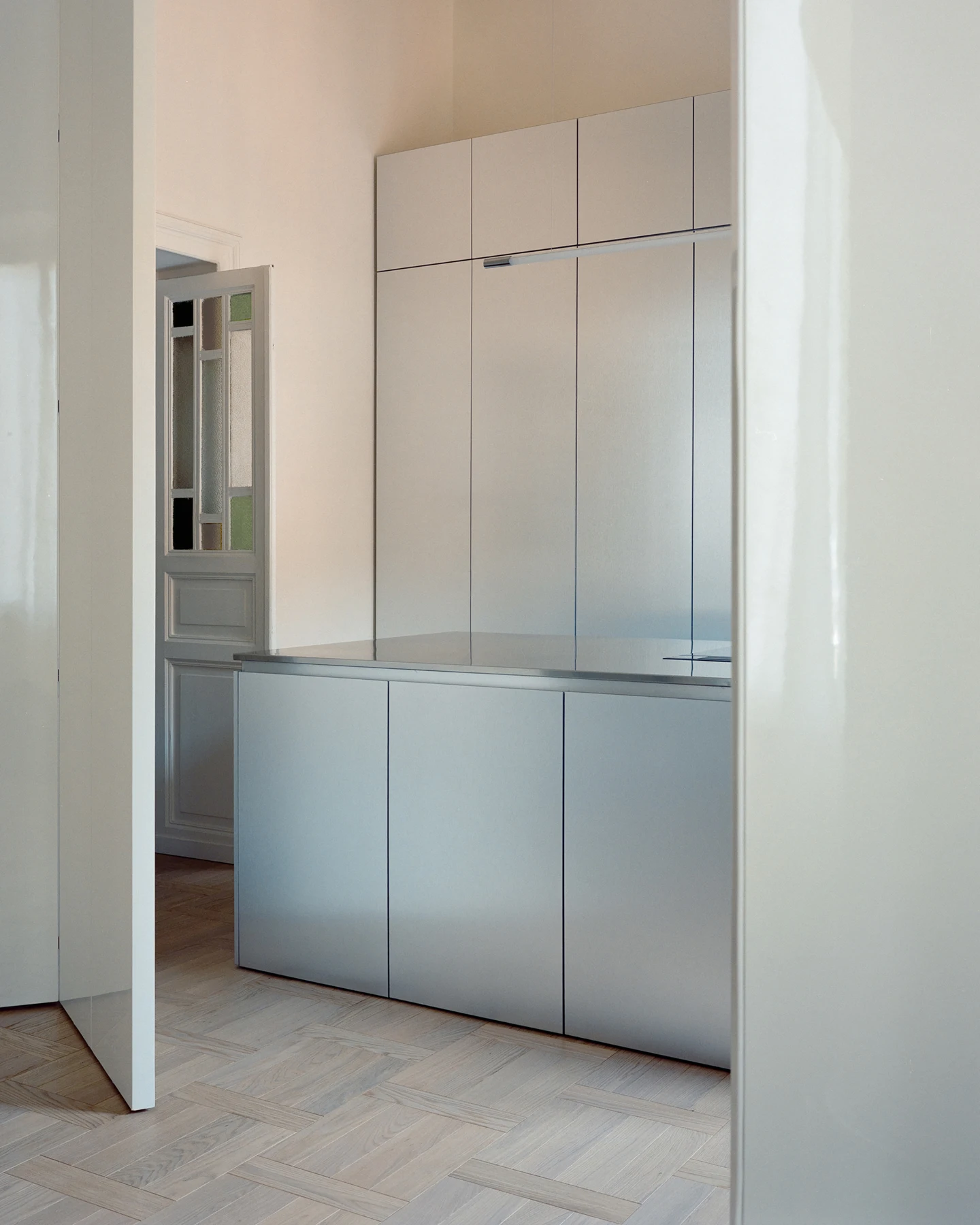 Close view of reflective metal island and flush full-height kitchen panels